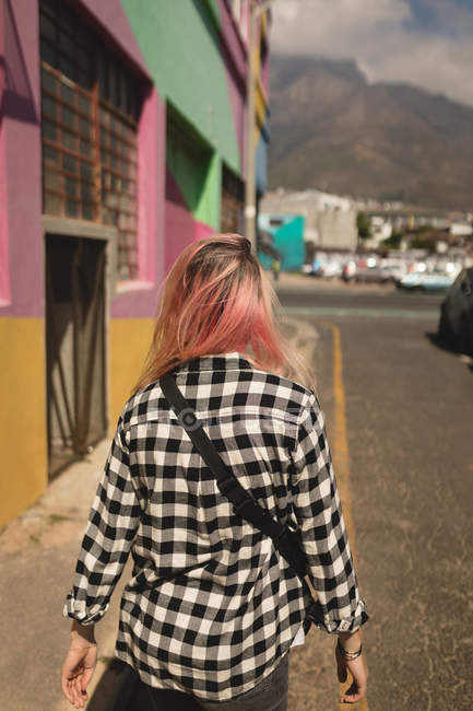 Vue arrière d'une jeune femme marchant sur une route — Photo de stock