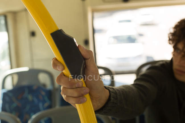 Hombre pulsando el botón en el poste mientras viaja en el autobús - foto de stock