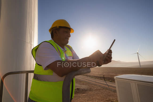 Інженер, який використовує цифровий планшет біля входу на вітроелектростанцію — стокове фото