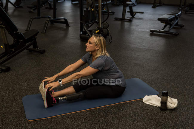 Femme handicapée effectuant des exercices d'étirement dans la salle de gym — Photo de stock