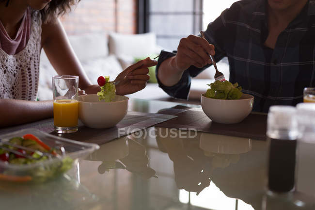 Partie médiane du couple prenant le petit déjeuner sur la table à manger à la maison — Photo de stock