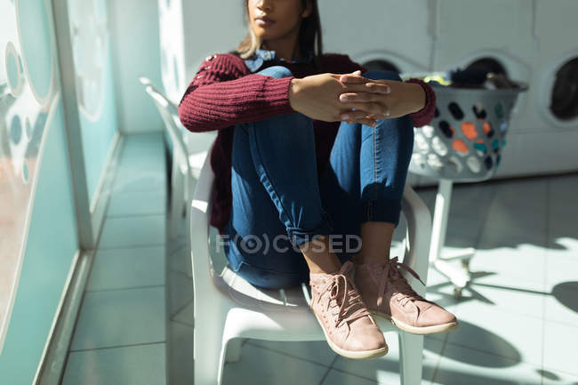 Jovem mulher olhando pela janela enquanto espera na lavanderia — Fotografia de Stock