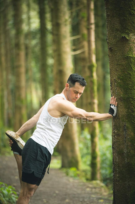 Adatto uomo facendo esercizio di stretching nella foresta — Foto stock