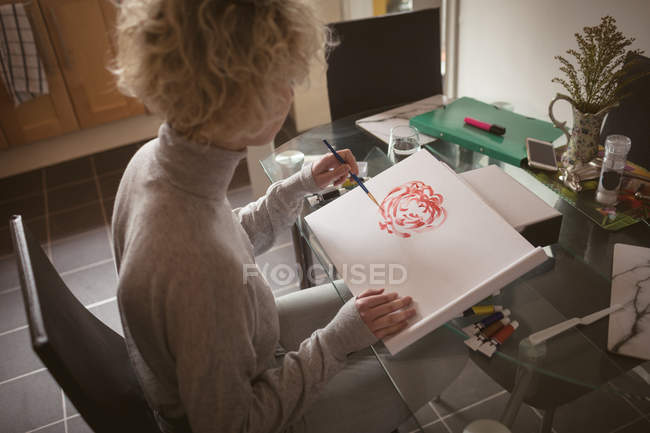 Young woman coloring a sketch at home — Stock Photo