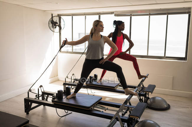 Dos mujeres haciendo ejercicio en la máquina de estiramiento en el gimnasio - foto de stock