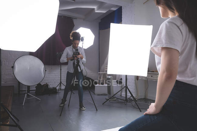 Fotógrafo do sexo feminino clicando fotos do modelo no estúdio de fotografia — Fotografia de Stock