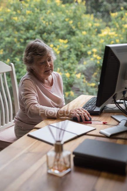 Seniorin benutzt zu Hause einen Desktop-Computer — Stockfoto