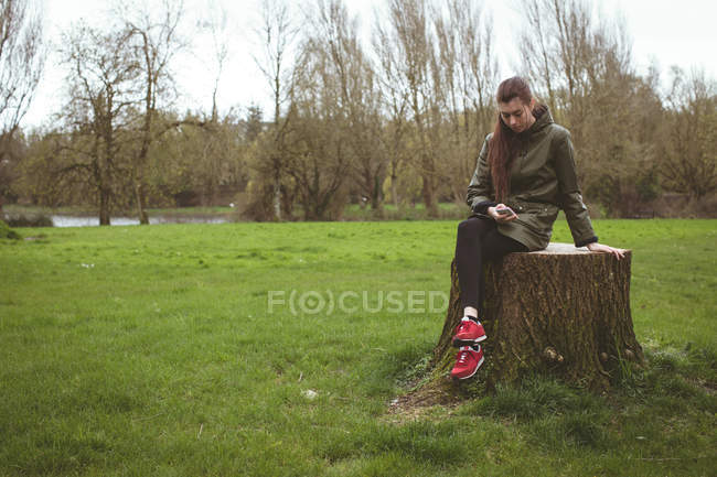 Красивая женщина с помощью мобильного телефона в парке — стоковое фото