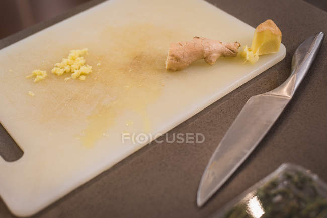 Крупный план разделочной доски с ножом и имбирем на кухне дома — стоковое фото