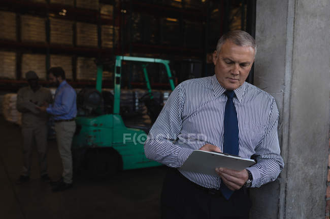 Мужчина-менеджер, пишущий на планшете на складе — стоковое фото
