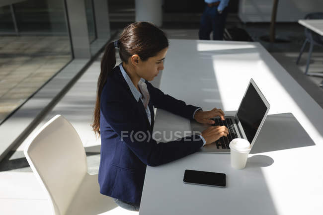Концентрована бізнес-леді використовує ноутбук в офісі — стокове фото