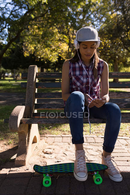 Mulher ouvindo música no parque em um dia ensolarado — Fotografia de Stock