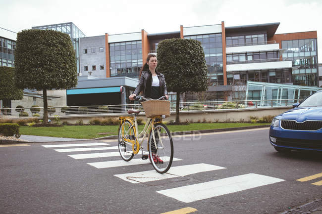 Hermosa mujer con bicicleta cruzando la carretera - foto de stock