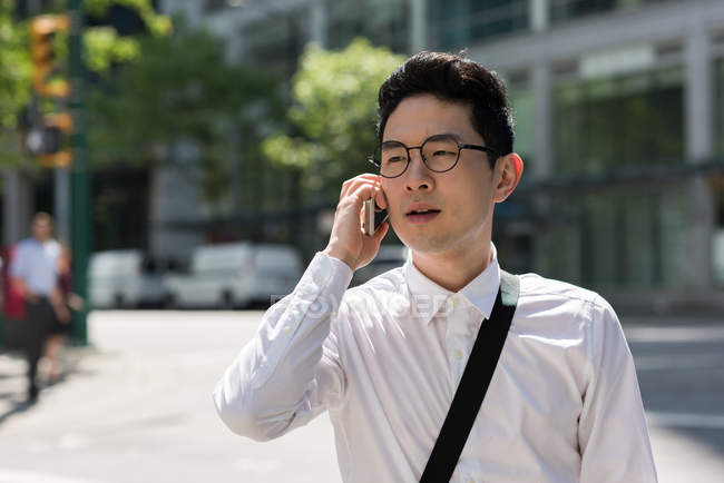Молодий чоловік розмовляє по мобільному телефону під час ходьби на вулиці — стокове фото