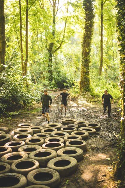 Fit men training over tyres obstacle course at boot camp — Stock Photo