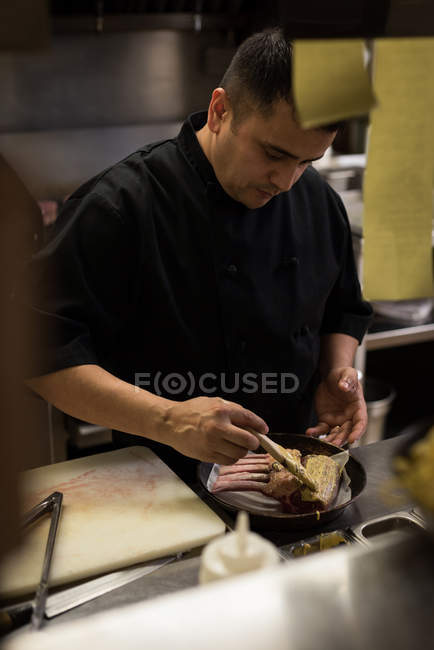 Chef masculino preparando carne en la cocina del restaurante - foto de stock