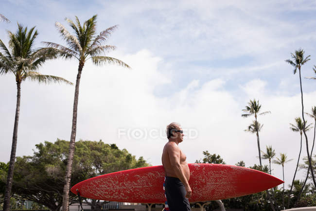 Чоловічий серфер тримає дошку для серфінгу на пляжі — стокове фото
