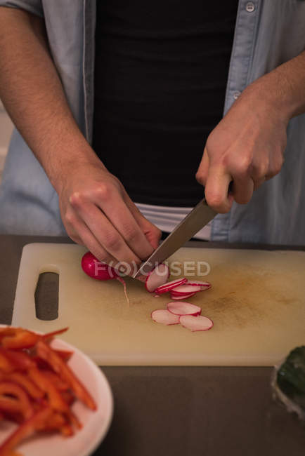 Woman cutting turnip in kitchen at home — Stock Photo