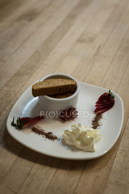 Rusk with cream in a plate on wooden platform — Stock Photo