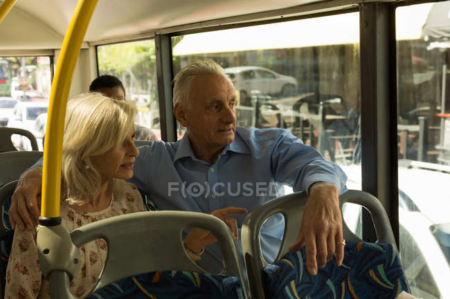 Pareja mayor interactuando mientras viaja en el autobús - foto de stock