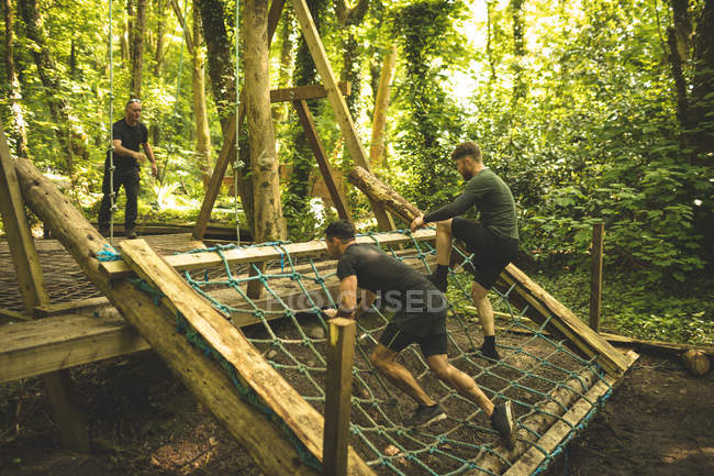 Ajuste los hombres que entrenan sobre carrera de obstáculos en el campo de entrenamiento - foto de stock