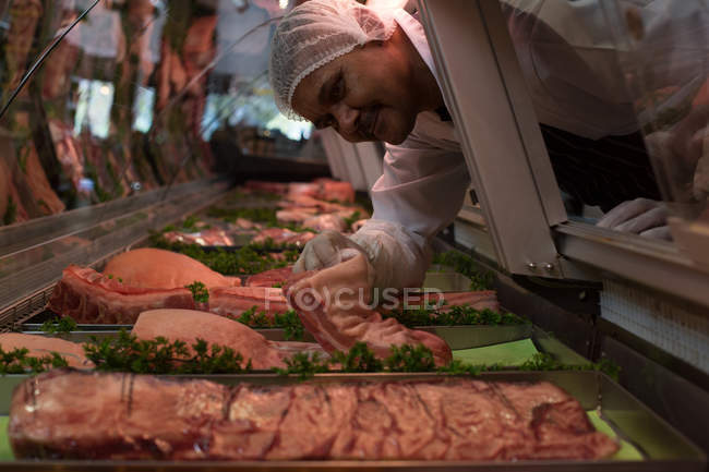 Metzger entfernt Fleisch aus Auslage in Metzgerei — Stockfoto