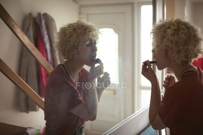 Jeune femme appliquant rouge à lèvres à la maison — Photo de stock