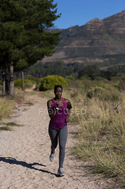 Deportista femenina decidida corriendo en el bosque - foto de stock
