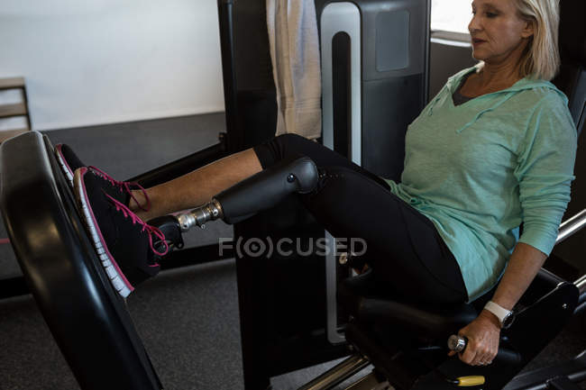 Behinderte Frau trainiert an Gerät im Fitnessstudio — Stockfoto