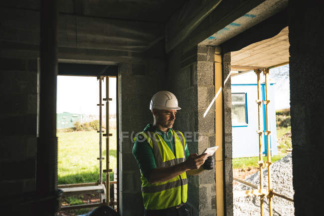 Engenheiro concentrado usando tablet digital dentro do prédio em construção — Fotografia de Stock
