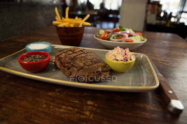 Hamburguesa de carne con papas fritas servidas sobre mesa de madera - foto de stock