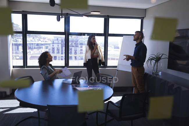 Бізнес-керівники обговорюють через дошку в офісі — стокове фото