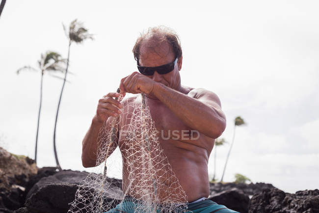 Pescatore che tiene la rete da pesca sulla spiaggia — Foto stock