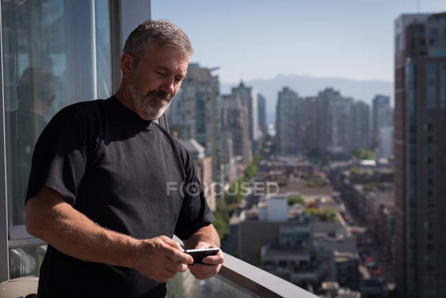 Чоловік використовує мобільний телефон на балконі вдома — стокове фото