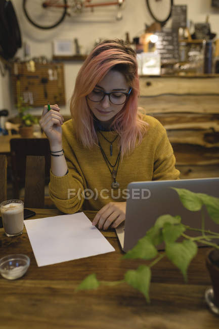 Молода жінка нотує в кав'ярні — стокове фото