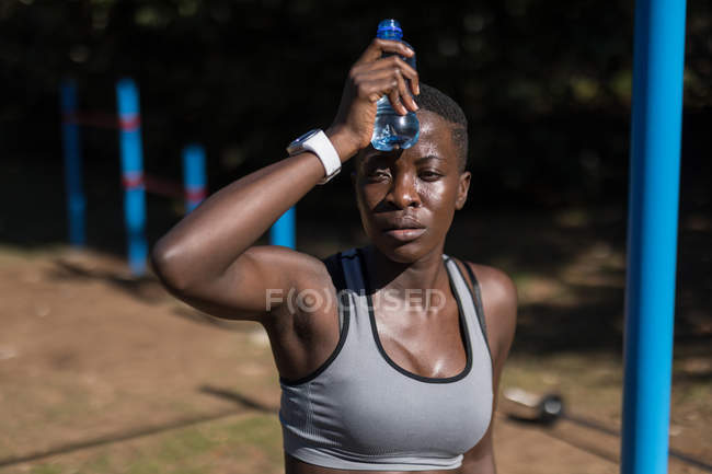 Крупним планом виснажена жінка-спортсменка з пляшкою води — стокове фото
