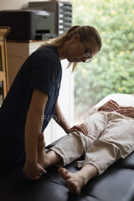 Physiotherapist giving a leg massage to senior woman at home — Stock Photo