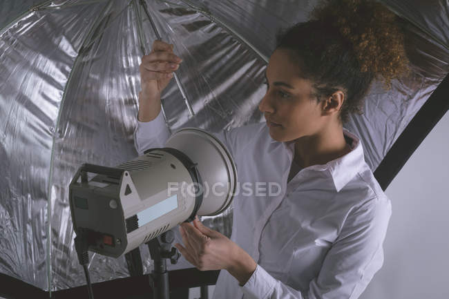 Fotografo femminile che regola le luci stroboscopiche in studio fotografico — Foto stock