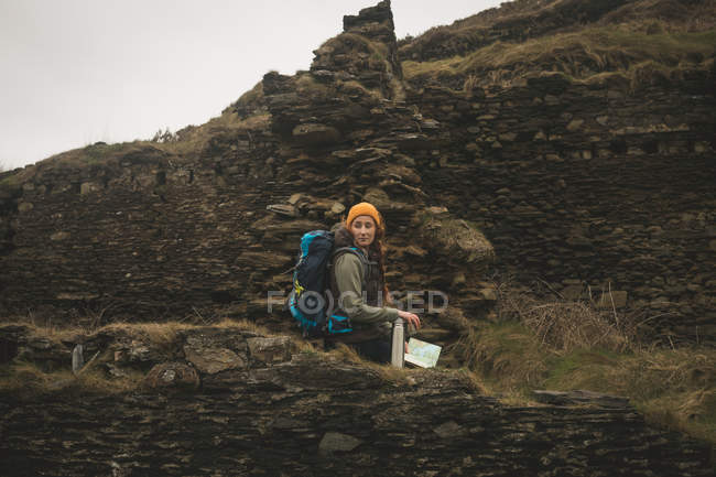 Vue latérale d'une randonneuse assise sur le mur de pierre abandonné — Photo de stock