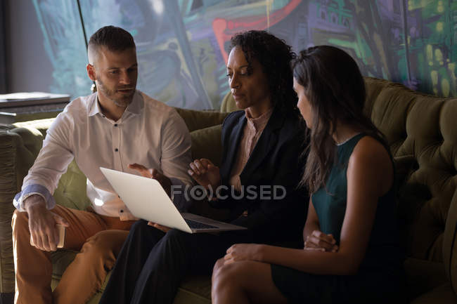 Business executives sitting sofa and discussing over laptop at office — Stock Photo