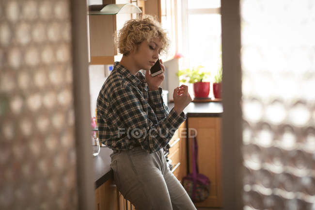 Female blogger talking on mobile phone at home — Stock Photo