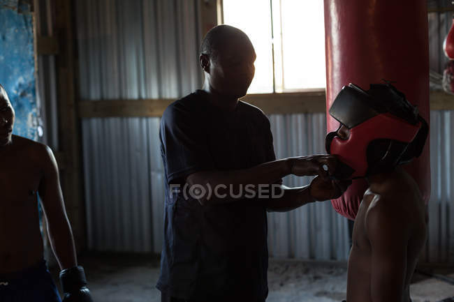 Тренер помогает боксеру носить головные уборы в фитнес-студии — стоковое фото