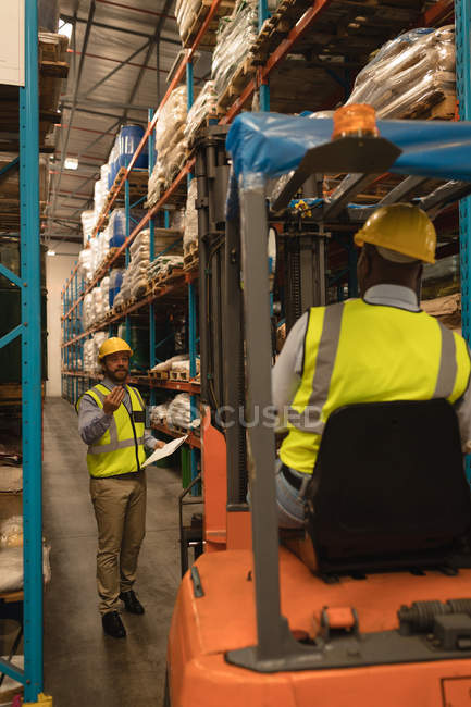 Travailleurs masculins interagissant les uns avec les autres dans l'entrepôt — Photo de stock