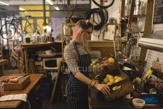 Mujer joven colocando una bandeja de verduras en el mostrador de la cocina en la cafetería - foto de stock
