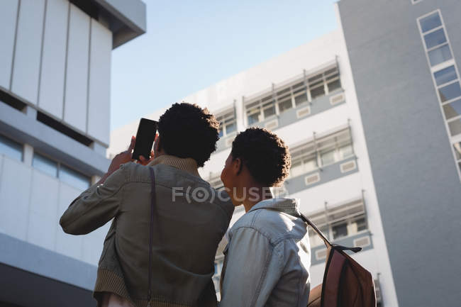 Gêmeos clicando foto com telefone celular na rua da cidade — Fotografia de Stock