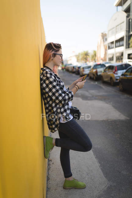 Молода жінка використовує мобільний телефон на тротуарі — стокове фото
