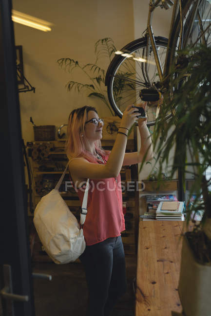 Молода жінка фотографує велосипед у кав'ярні — стокове фото