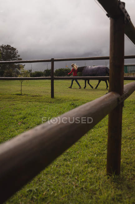 Adolescente caminhando com cavalo no rancho — Fotografia de Stock