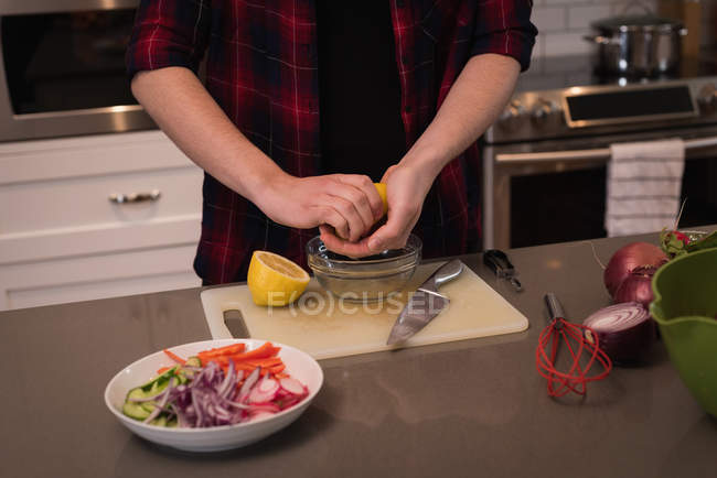 Femme serrant du citron dans la cuisine à la maison — Photo de stock
