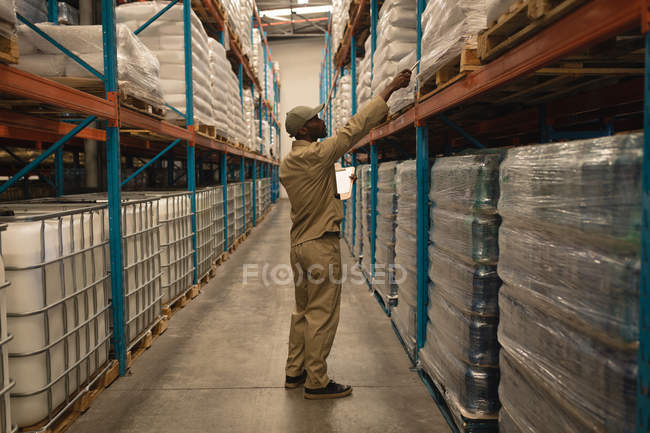 Чоловік працівник перевіряє запаси на складі — стокове фото